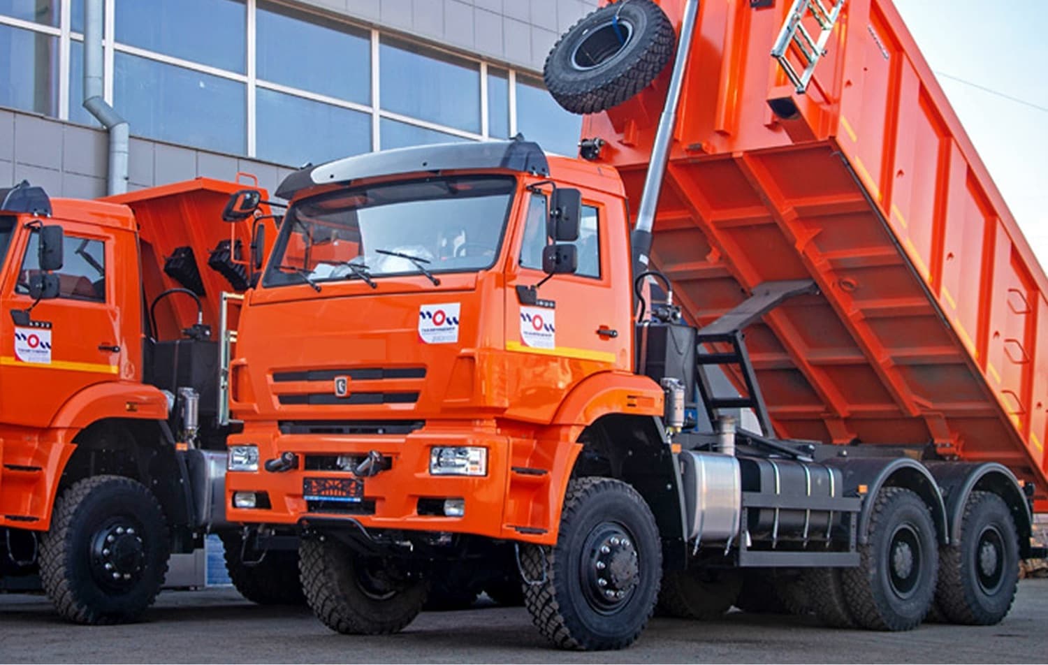 Fleet of orange dump trucks parked in a yard